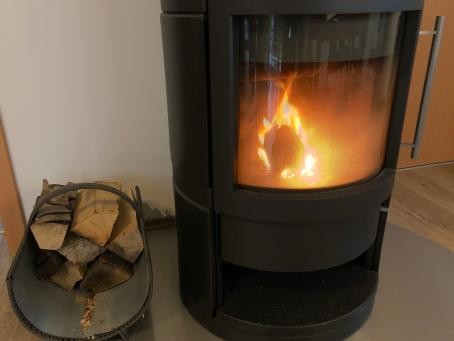 Ein Wohnzimmer mit einem kleinen Kamin, in dem ein Feuer brennt.